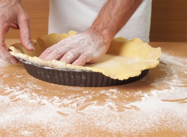 man pressing dough crust above tin