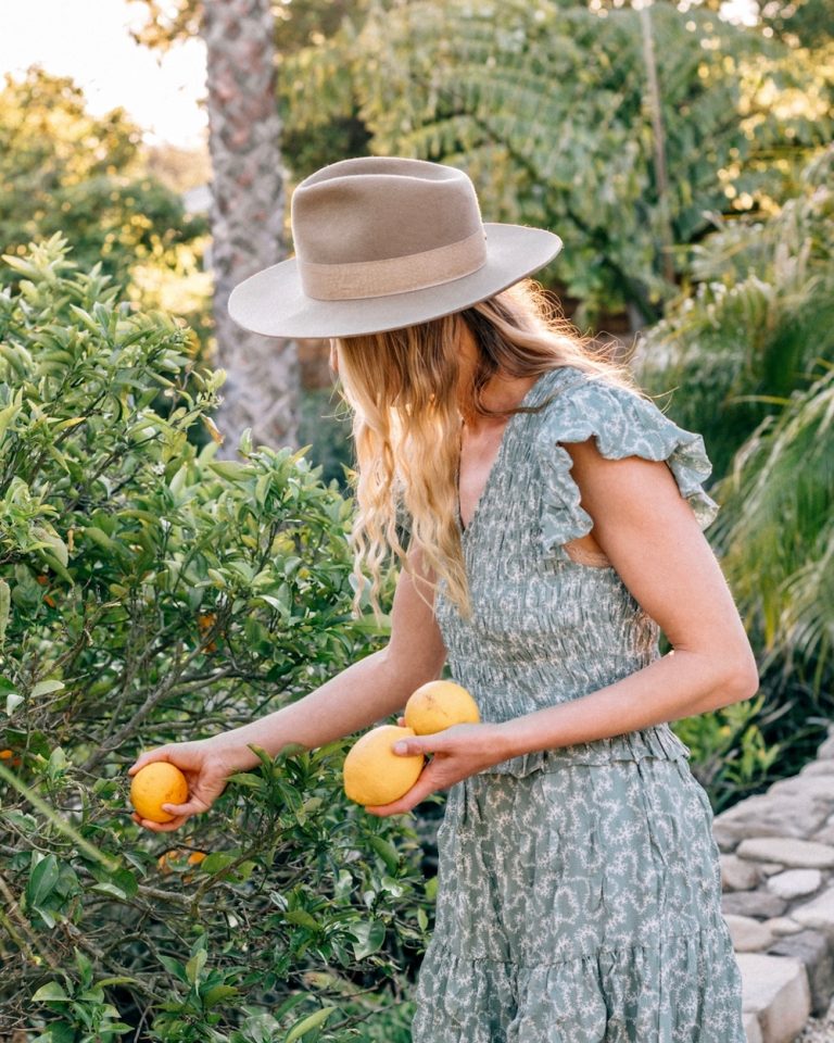 Blond woman picking lemons outside.