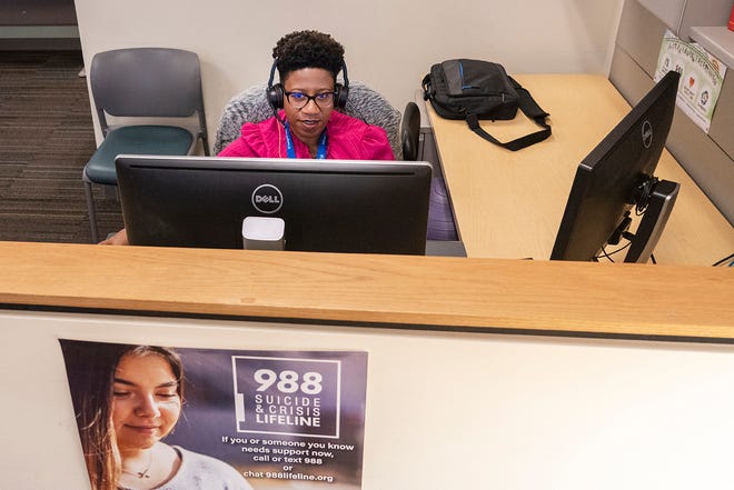 Studio manager Jaime Parker takes calls on the crisis hotline Wednesday.
