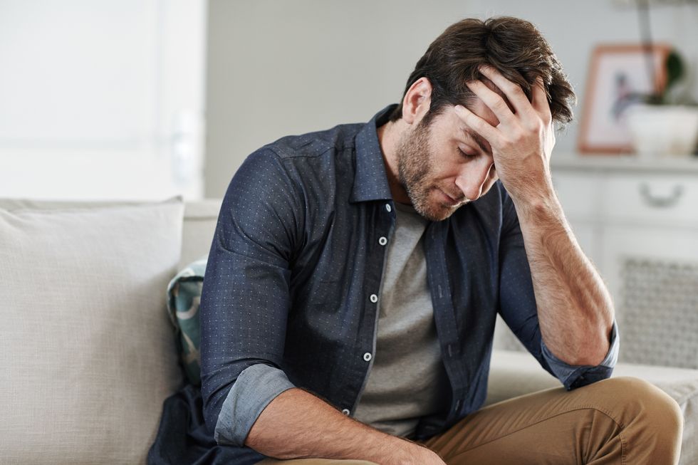 man sitting alone at home looking sad and upset