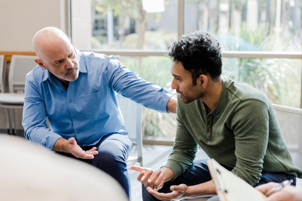 older man helps younger man verbalize problems in therapy