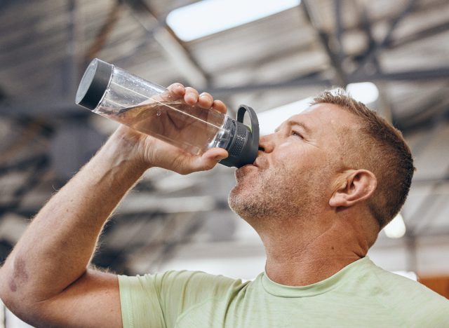 mature man drinking bottle of water during workout