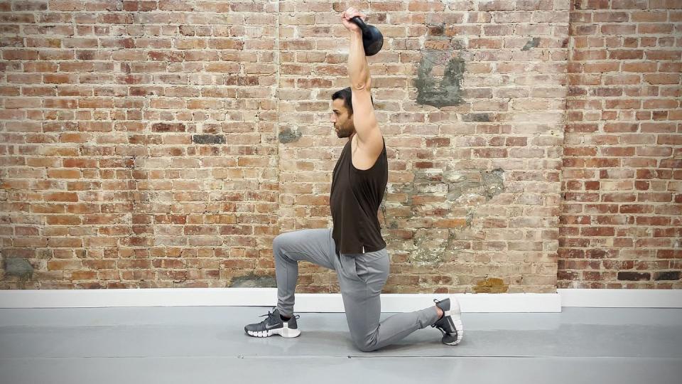 Tamir practices the one-and-a-half kneeling overhead press exercise