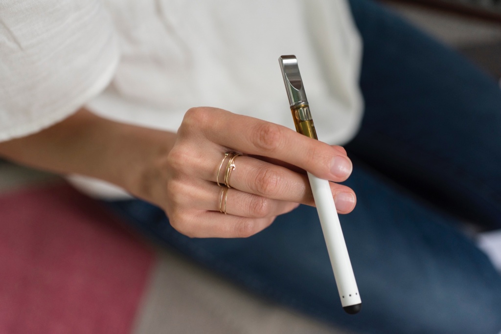hand holding a vape cart consumes cannabis