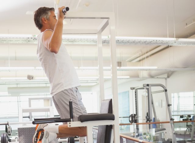 mature man doing pull-ups in the gym