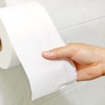 close up of woman's hand pulling toilet paper