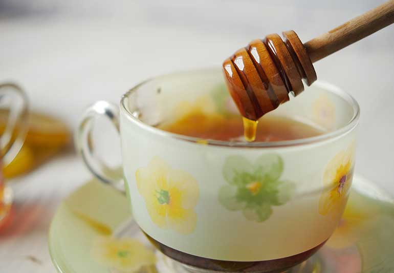 raw honey poured into cup of tea