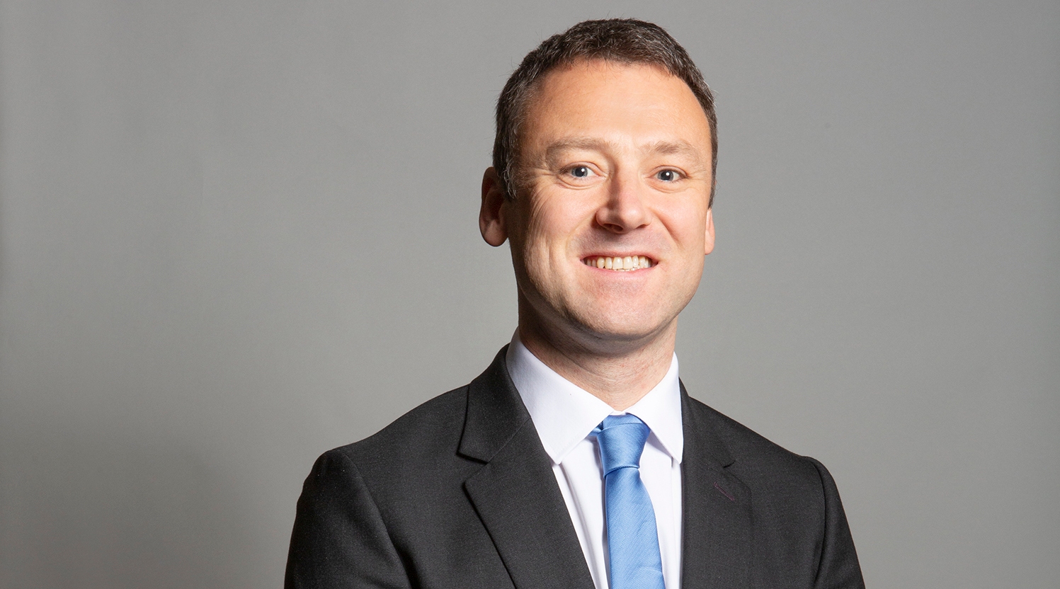 Conservative MP Brendan Clarke-Smith standing in blue suit and tie against gray background