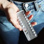 A woman holds a strip of birth control pills