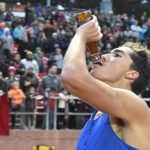 corey bellemore drinks a bottle of beer during a race