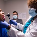 The doctor examines the young patients throat.