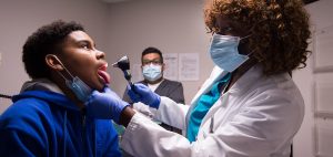 The doctor examines the young patients throat.