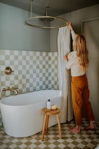 Woman hanging the shower curtain in a quirky modern bathroom.