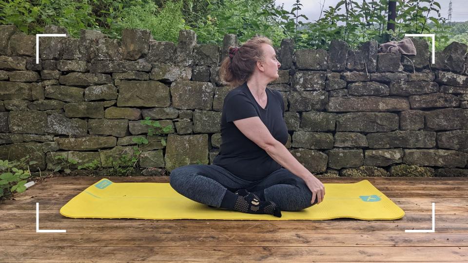 Samantha Priestley stretching during her yoga routine, sitting on a mat in the garden, she's part of yoga every day