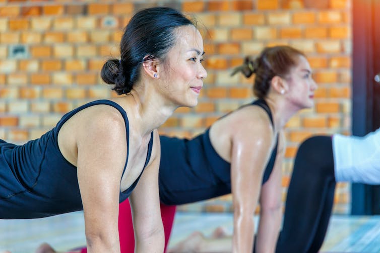 Women in hot sweating yoga studio.