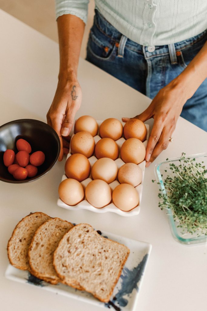 Woman having breakfast with bread, eggs and tomatoes.