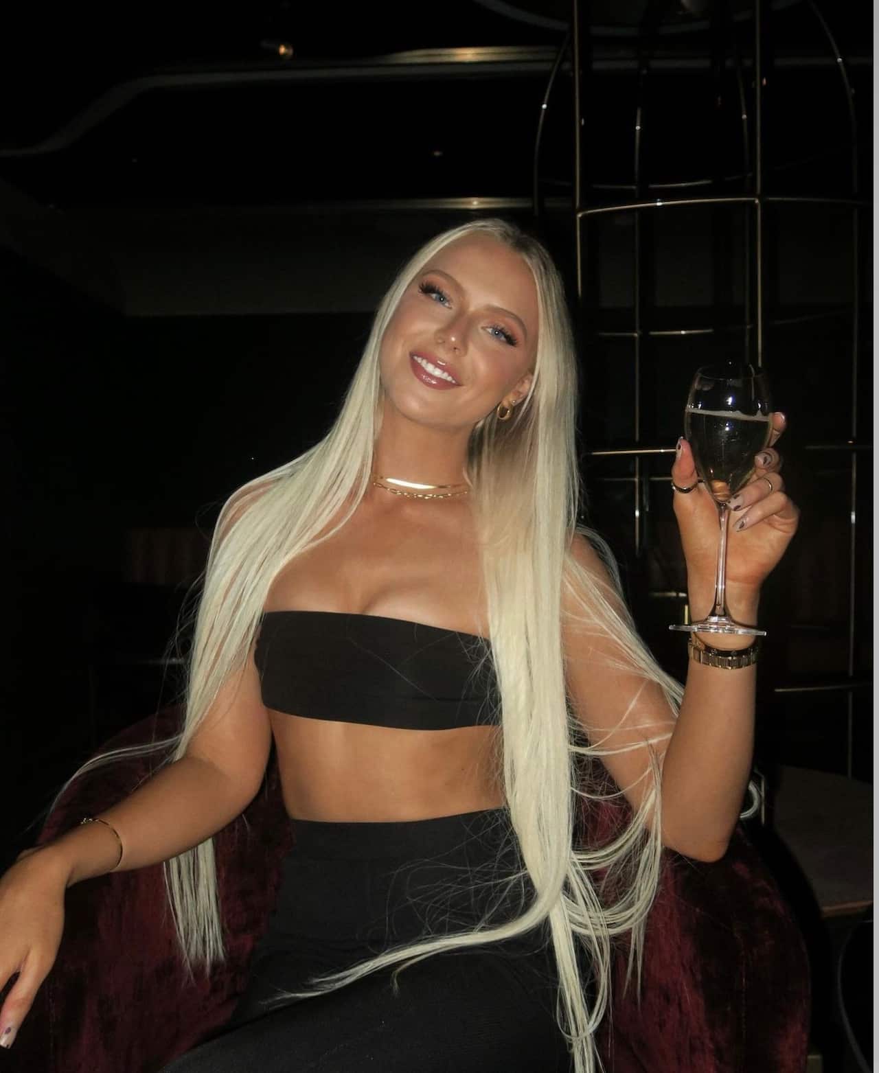 A young woman in a chair holding a glass of champagne