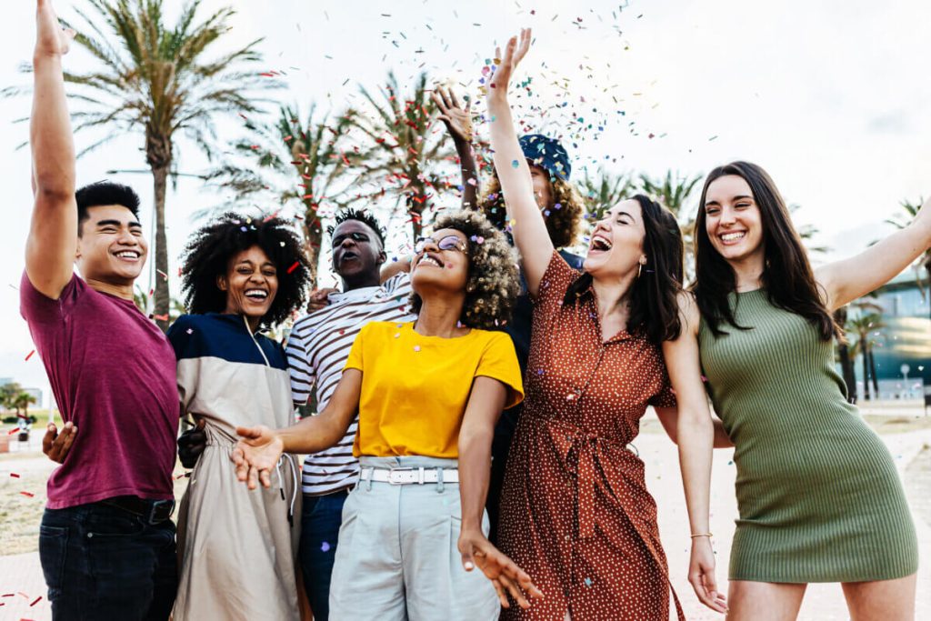 Young adult friends having fun and partying together on the beach