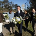 People walking by the roadside carrying bouquets of flowers