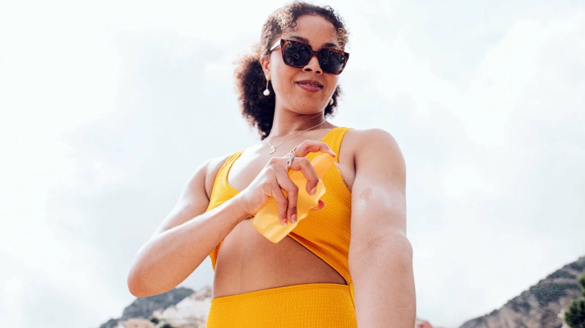 A woman applying sunscreen outdoors.